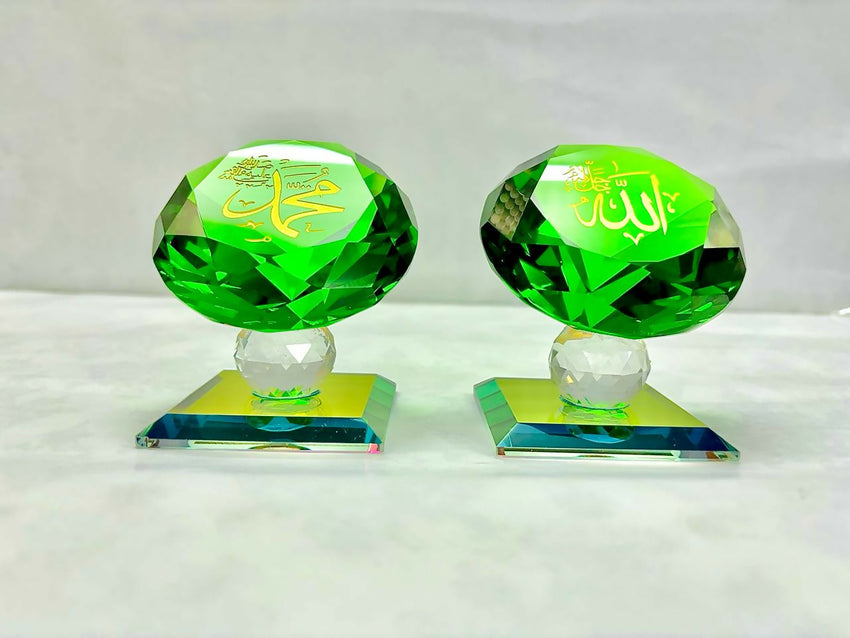 A pair of green crystal souvenirs featuring the names "Allah" and "Mohammad" in elegant gold Arabic calligraphy, mounted on a clear faceted base.