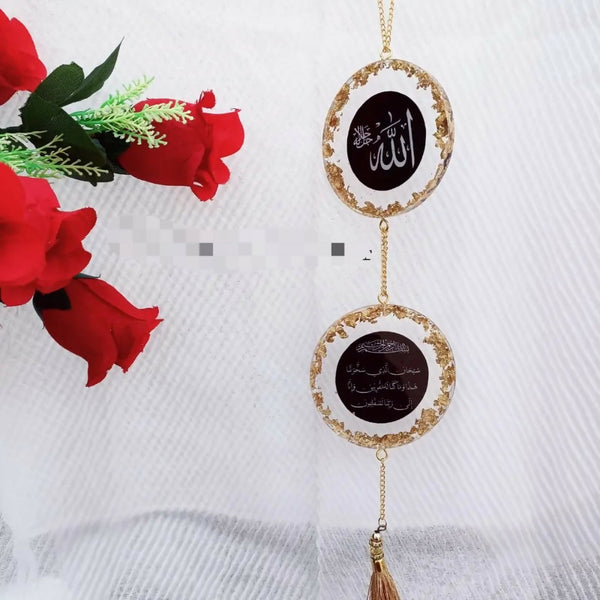 Elegant double-layered Islamic car hanging with a protective dua, designed for rearview mirror decoration. Made from high-quality materials with intricate craftsmanship, this hanging features gold detailing, the name of Allah, and a dua for protection. It is adorned with a gold chain and tassel, and is beautifully displayed next to red roses.